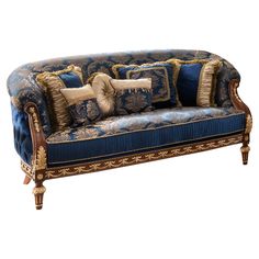 a blue couch with gold trim and pillows on it's back, sitting against a white background