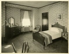 an old black and white photo of a bedroom with a bed, dresser, mirror and chair