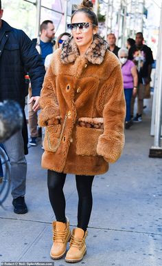 a woman walking down the street in a fur coat