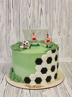 a cake with soccer players on it sitting in front of a white fence and green grass