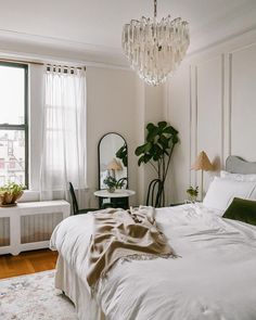 a bedroom with a large bed and a chandelier hanging from the ceiling