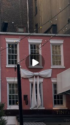 a pink building with white drapes on it's windows