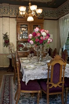 the dining room table is set with flowers in vases and plates on the table