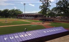 a baseball field that has some people playing on the field and fans in the bleachers