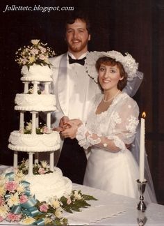 a man and woman standing next to each other in front of a large wedding cake