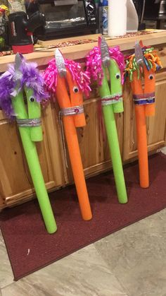 three plastic carrots with faces on them are sitting in front of a kitchen counter