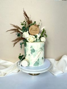 there is a cake with flowers on the top and leaves on the bottom, sitting on a plate