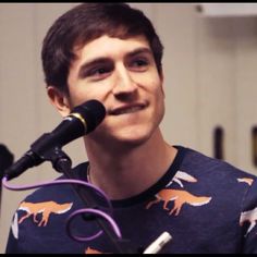 a man with a mustache standing in front of a microphone