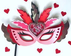 a pink mask with red hearts on it and a black stick sticking out of it