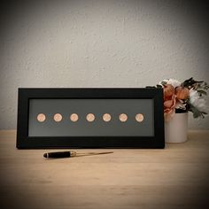 a black frame with pink polka dots on it and a pen sitting next to it