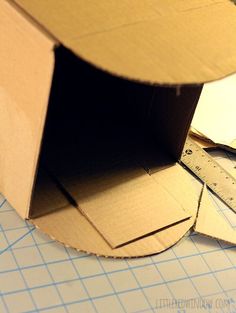 an open cardboard box sitting on top of a piece of paper next to a pair of scissors