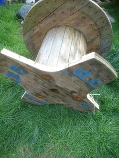 a wooden chair sitting on top of green grass next to a hose spoole