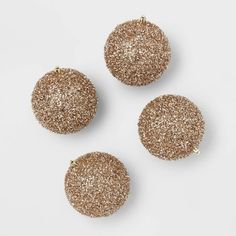 three gold glittered round ornaments on a white surface