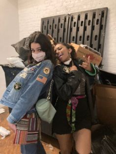 two young women standing next to each other in front of a pile of boxes and bags