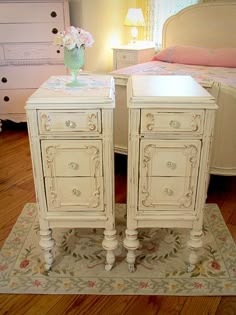 two white nightstands sitting on top of a rug