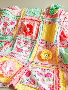 a pink and green quilted blanket with flowers on the top, sitting on a white crib