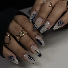 a woman's hands with white and blue nail polishes on their nails, holding gold rings