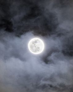 the full moon is seen through dark clouds