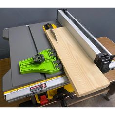 a table sawing machine with two green blades on it's blade and some tools in the drawer