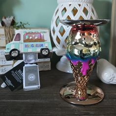 a colorful glass vase sitting on top of a wooden table next to other small items