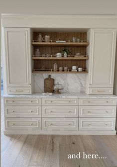 a kitchen with white cabinets and marble counter tops, along with an open shelving unit