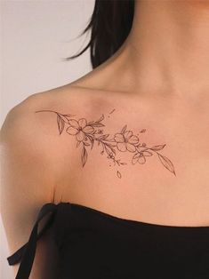 a woman's shoulder tattoo with flowers and leaves on the left side of her chest