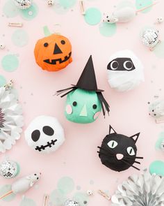 various halloween decorations are arranged on a pink background with silver and green confetti