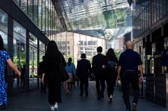 many people are walking down the walkway in an office building