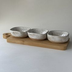 three white bowls sitting on top of a wooden tray