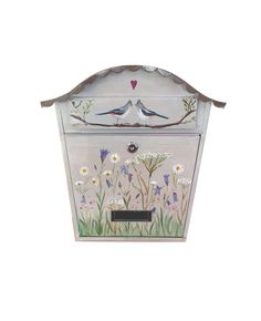 a white box with flowers and birds painted on the side, sitting in front of a white background