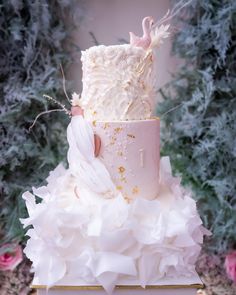 a three tiered cake with white frosting and pink icing