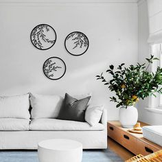 a living room with white furniture and three circular wall art hanging on the wall above it