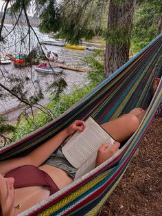 a woman laying in a hammock reading a book