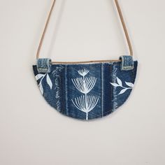 a denim purse with white flowers on it hanging from a string and two strings attached to the back