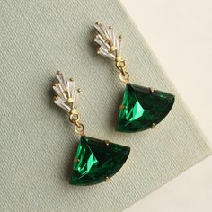 These emerald green art deco earrings feature a graduated geometric design.  The tiny cubic zirconia jewels are cut into perfect rectangles.  They remind us of classic Deco architecture, like the Chrysler building!  The classically cut fan shaped stone is also glass in a beautiful, rich emerald green shade.   The earrings measure 40mm (an inch and a half) in length and have gold plated ear wires.  The emerald fan stone is designed to hang just below the earlobe.   This piece of jewellery comes p Art Deco Drop Earrings, Jewelry Necklace Simple, Bijoux Art Deco, Art Deco Emerald, Woodland Earrings, Green Art Deco, Silk Purse, Deco Architecture, Cameo Earrings