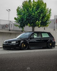 a black car parked next to a tree