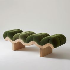 a green bench sitting on top of a white floor next to a wooden stand with four cushions