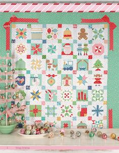 a quilted wall hanging next to a potted plant and christmas ornaments on a table