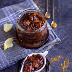 a glass jar filled with food sitting on top of a blue cloth next to spoons