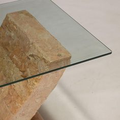 a glass and wood table with a rock on it's base in front of a white background