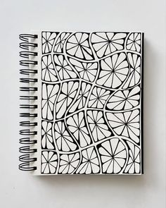 a black and white drawing on top of a spiral notebook with an abstract design in the middle