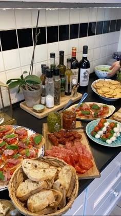 several plates of food on a counter with bottles of wine in the backgroud