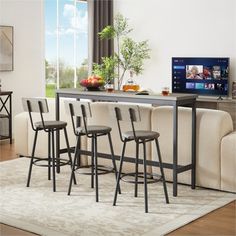 a table with four stools in front of it and a flat screen tv on the wall