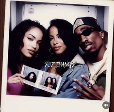 three people are posing for a photo with the same person holding up an album in front of them