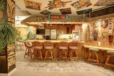 the inside of a tropical themed restaurant with tiki decorations on the ceiling and bar stools