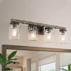 three mason jar lights are hanging on the bathroom mirror