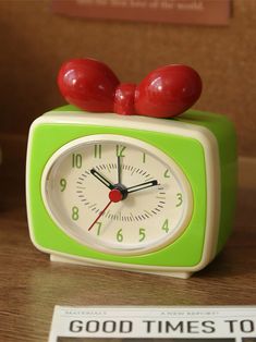 an alarm clock with two red cherries on it's face sitting on a table