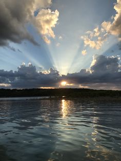 the sun is shining through clouds over water