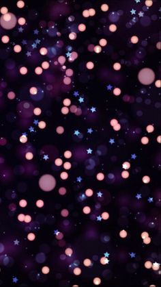 many pink and blue stars are in the dark night sky, with blurry lights