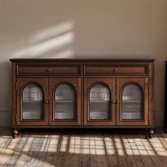 a wooden cabinet with glass doors in an empty room